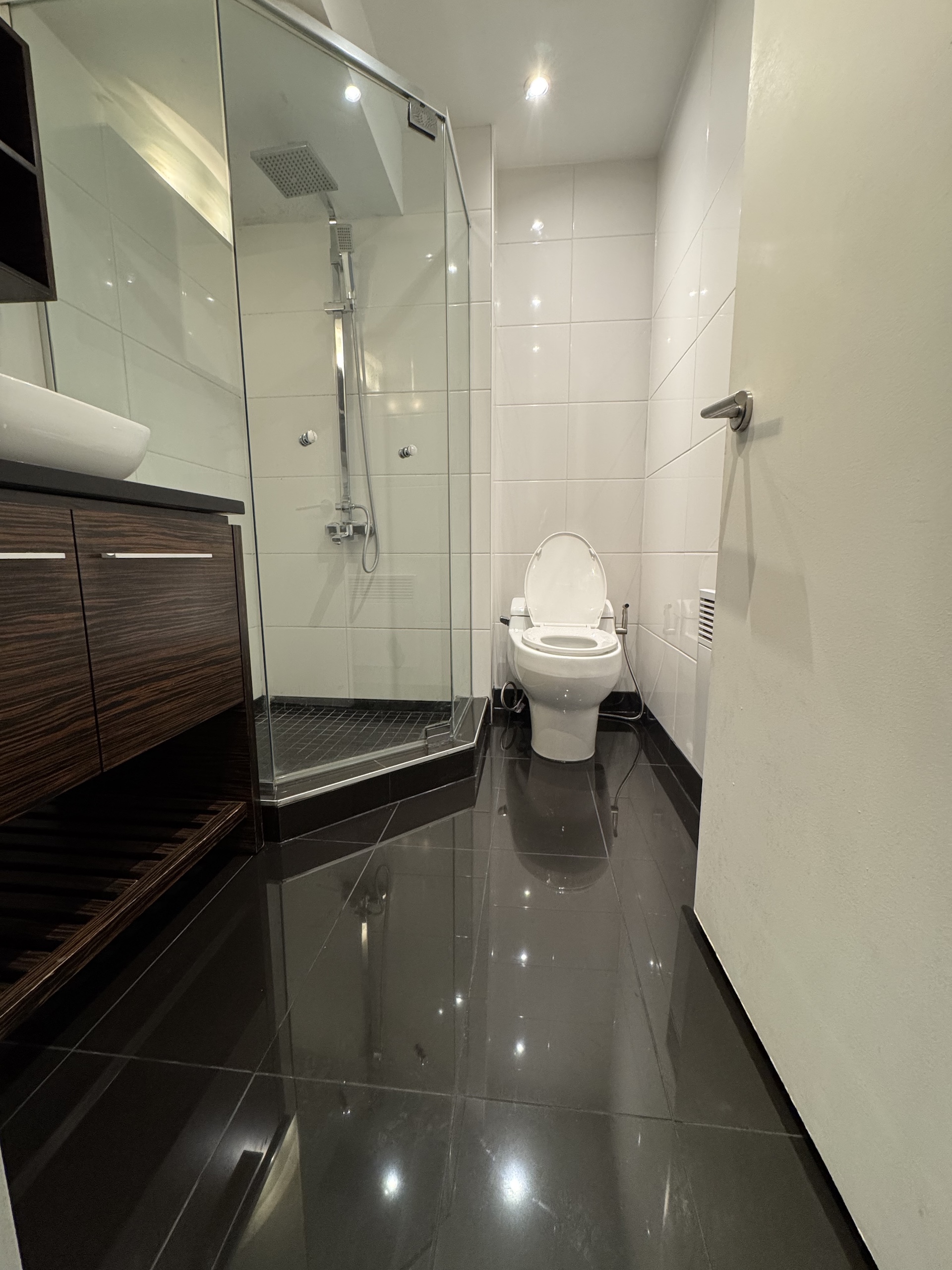 Corner glass shower enclosure installation in modern black tiled bathroom