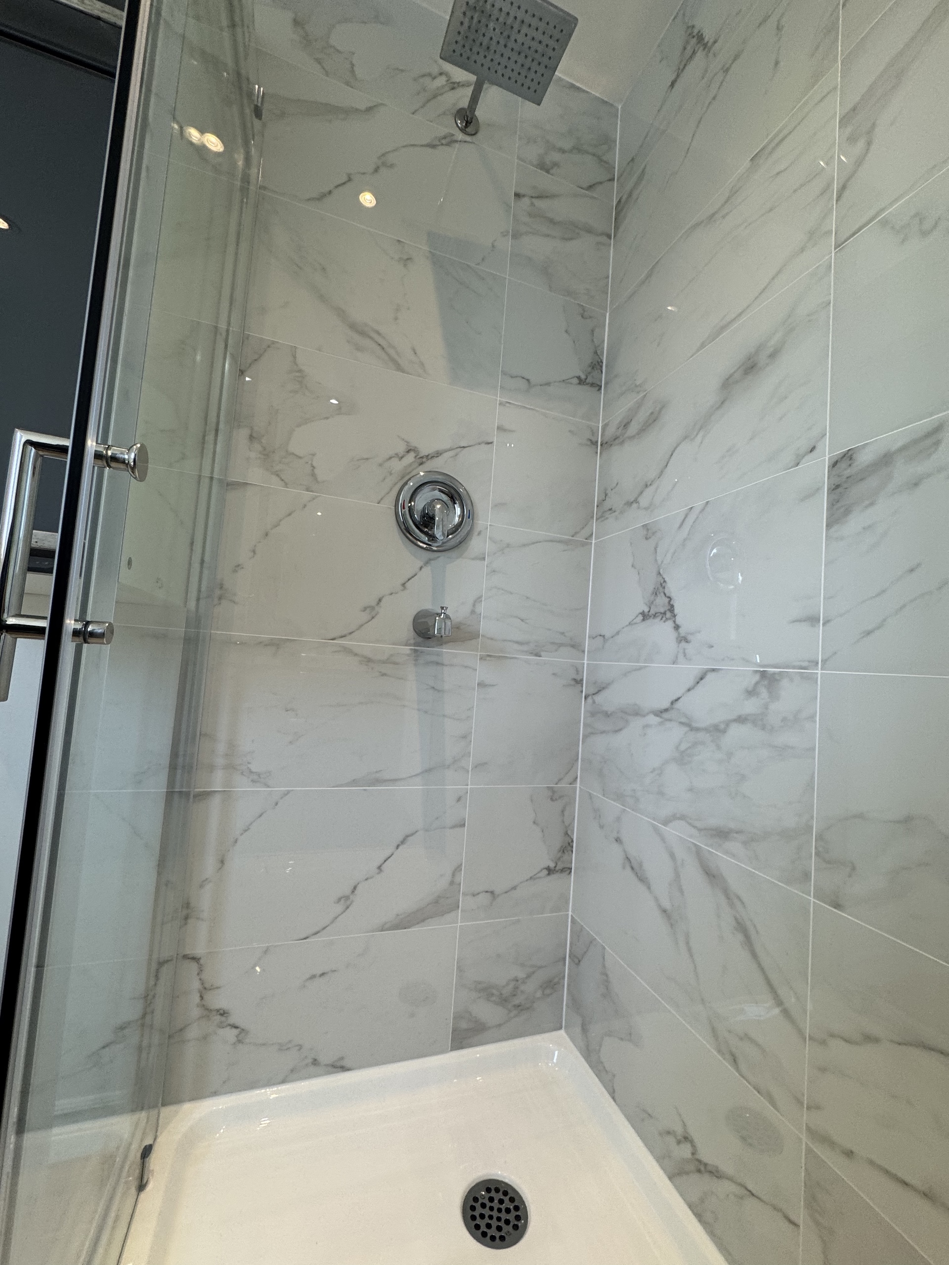 Modern chrome rainfall shower head system installation on marble tile