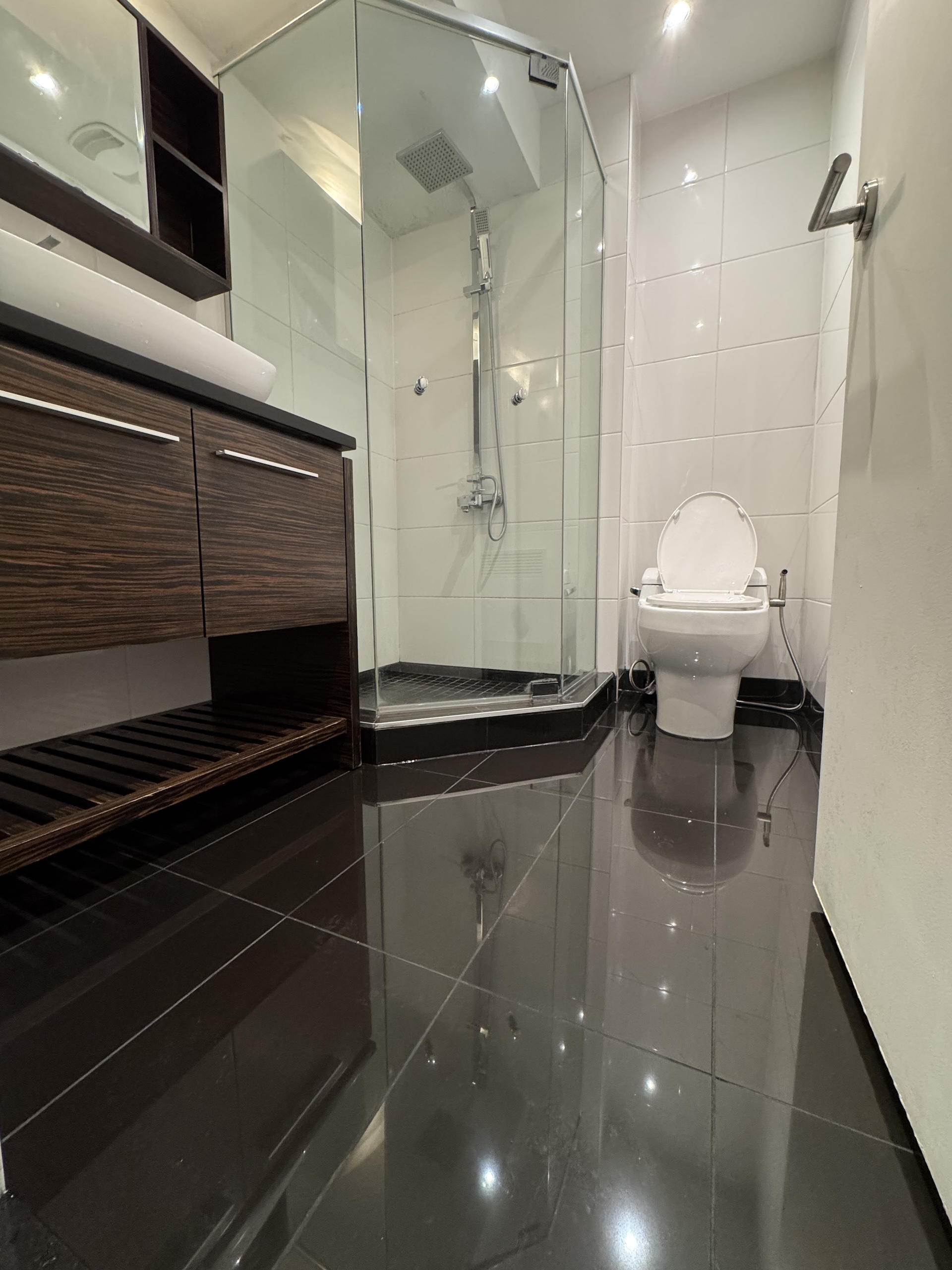 Contemporary bathroom design with high-gloss black floor tiles and floating vanity