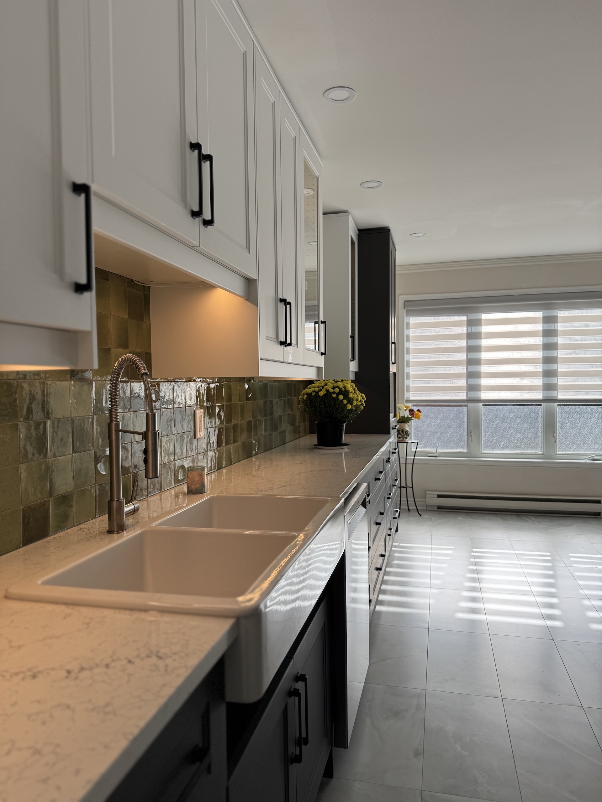 Detail shot of double basin farmhouse sink with green artisan backsplash tiles