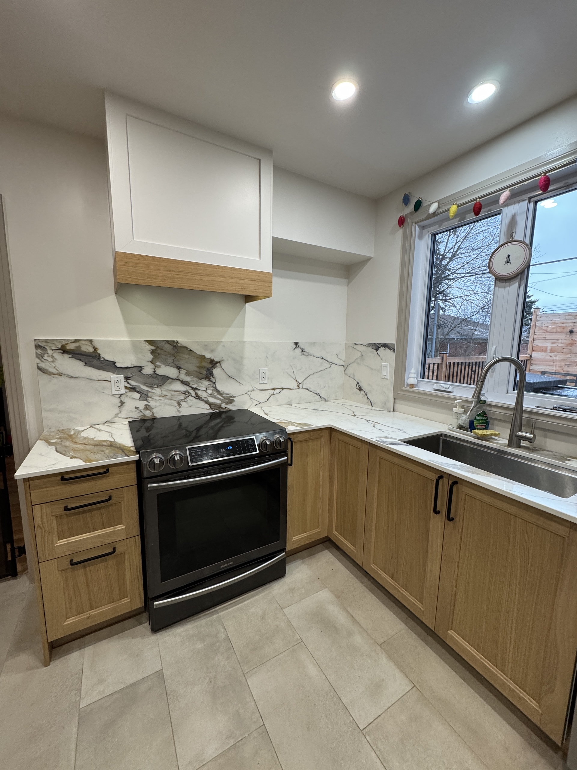 Modern kitchen with light oak cabinets and dramatic bookmatched marble backsplash