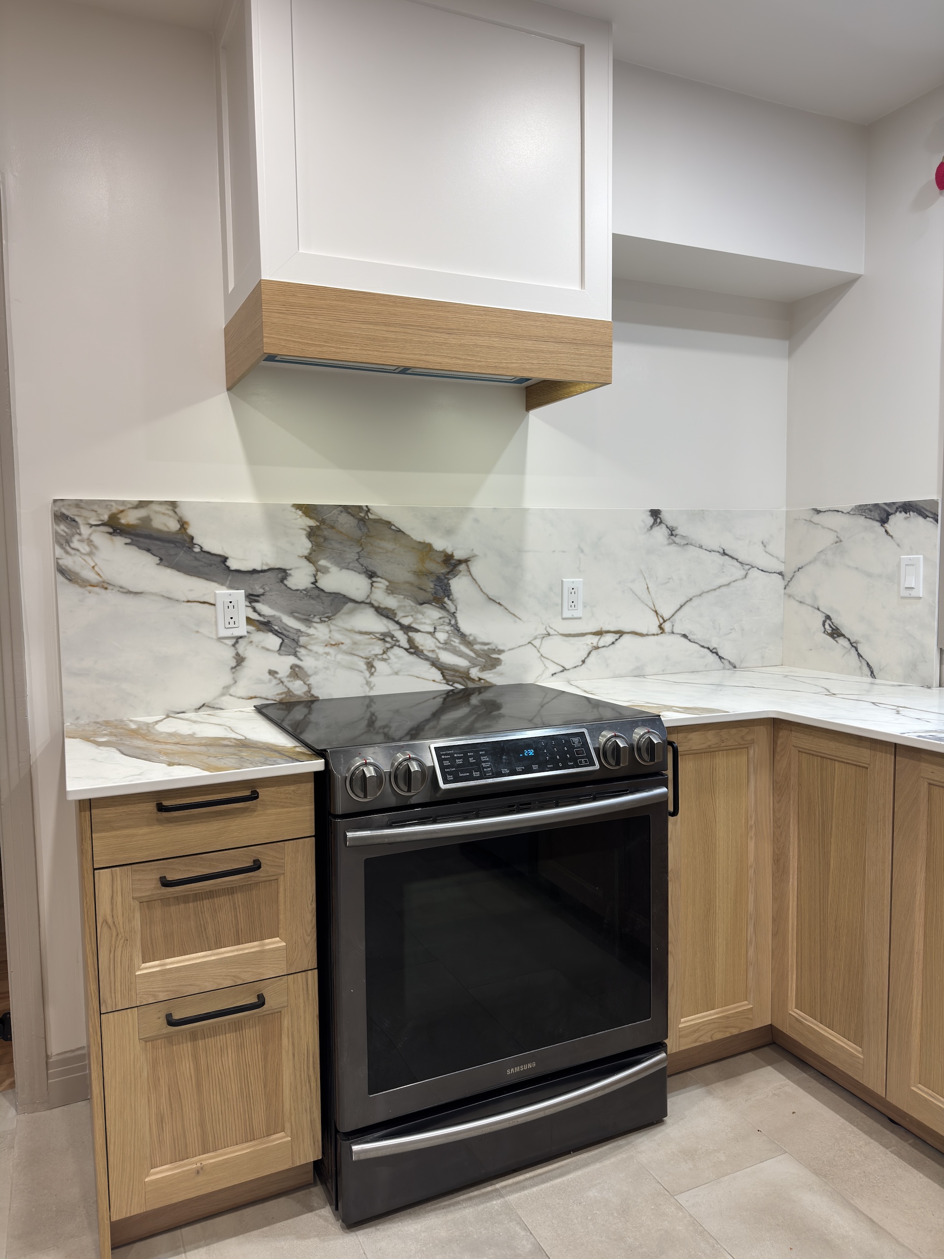 Detail view of porcelain slab backsplash and Samsung slide-in range